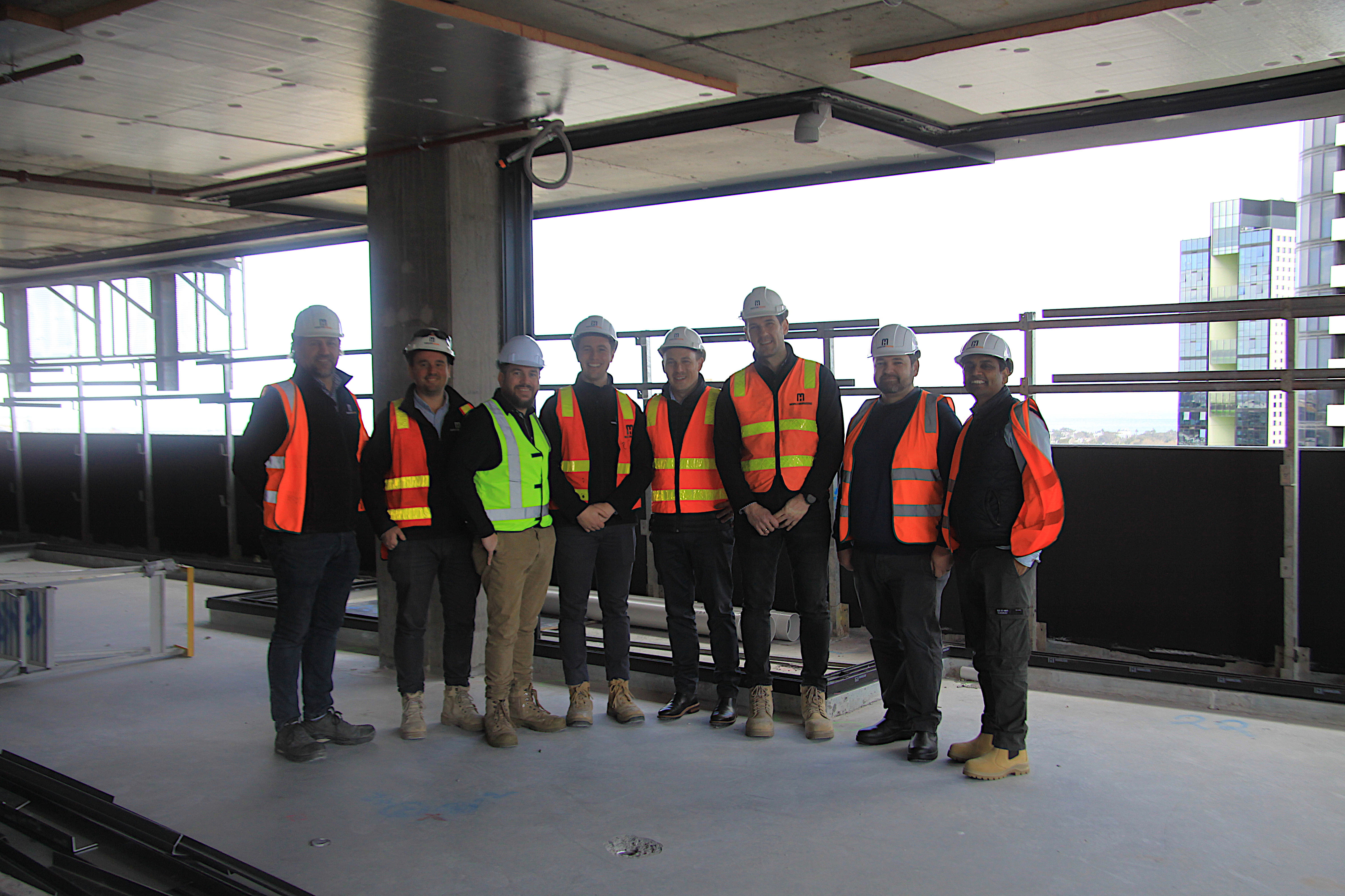 A group of people in high-vis vests and hard hats stand together on a construction site