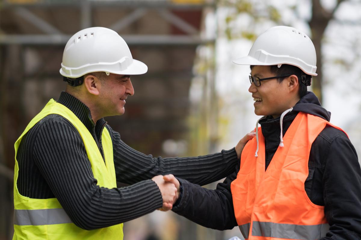 One worker clasping hands with and patting shoulder of second worker