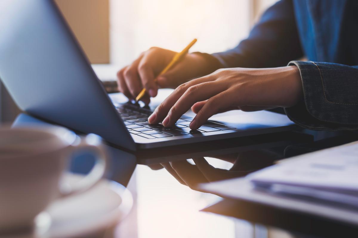 Photo of the hands of a person typing on a laptop