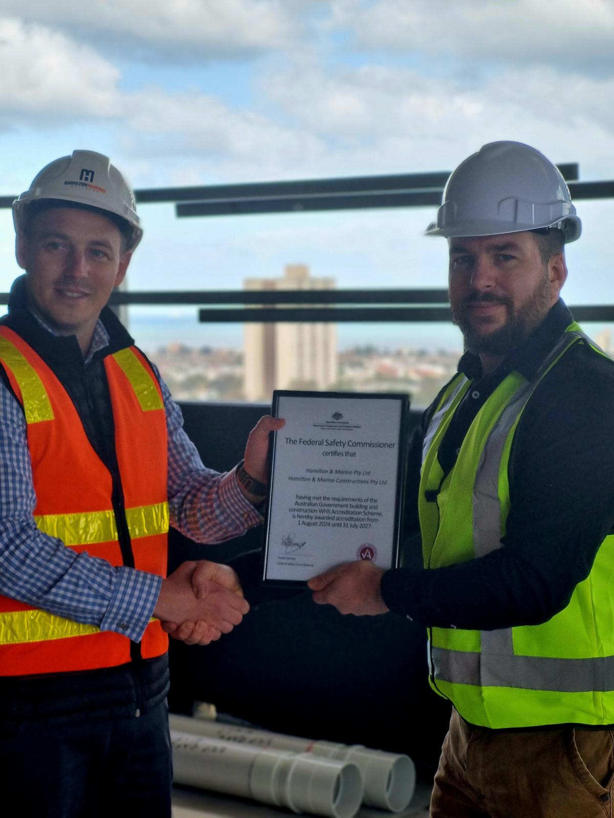 Two men in high-vis vests on a construction site shaking hands